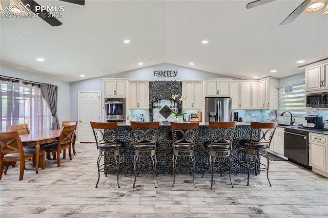 kitchen with decorative backsplash, ceiling fan, appliances with stainless steel finishes, a center island, and a sink