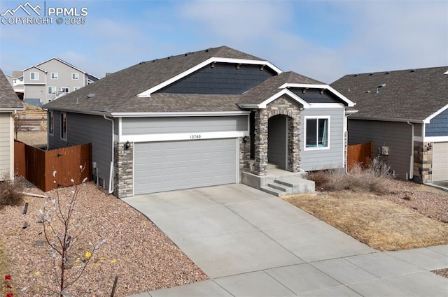 view of front of house featuring a garage, a shingled roof, fence, stone siding, and driveway