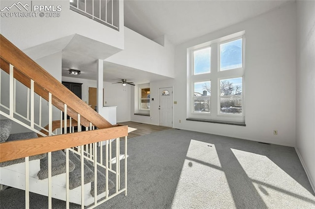 foyer entrance with stairs, a high ceiling, and dark carpet