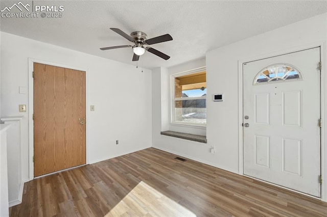 entryway with a textured ceiling, wood finished floors, visible vents, and a ceiling fan