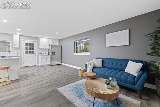 living area featuring light wood-style floors, baseboards, and recessed lighting