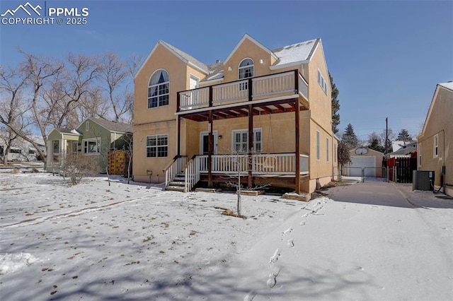 view of front of house with a garage, central AC, a balcony, and stucco siding