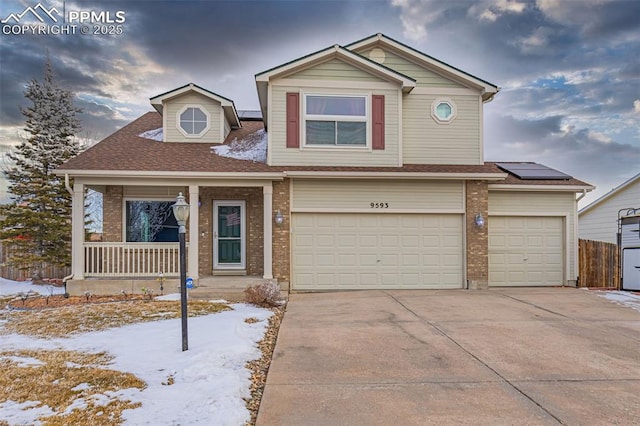 view of front of property with brick siding, solar panels, concrete driveway, covered porch, and an attached garage