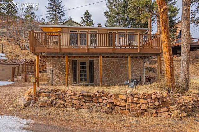 back of house with stone siding, stairway, and a wooden deck