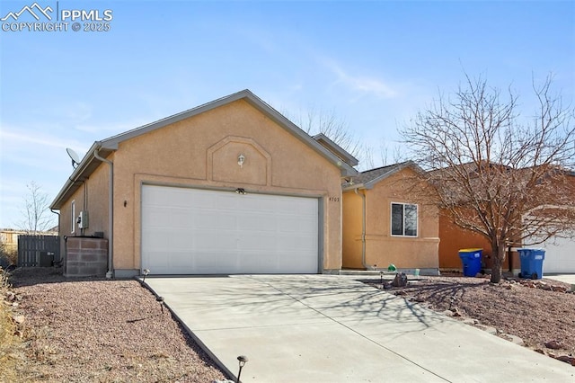 exterior space with an attached garage, central air condition unit, concrete driveway, and stucco siding