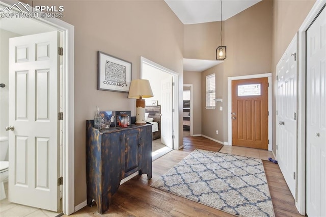 foyer with a high ceiling, baseboards, and wood finished floors