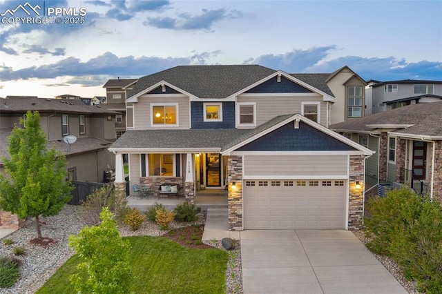 craftsman inspired home with a porch, an attached garage, a shingled roof, concrete driveway, and stone siding