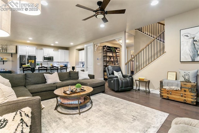 living room featuring recessed lighting, dark wood-type flooring, ceiling fan, baseboards, and stairs