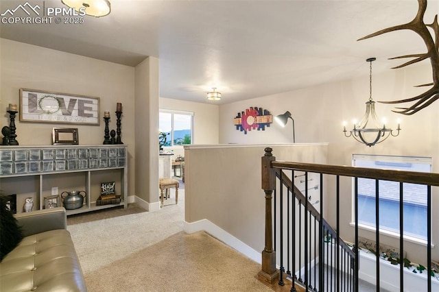 hall featuring baseboards, carpet floors, an upstairs landing, and a notable chandelier