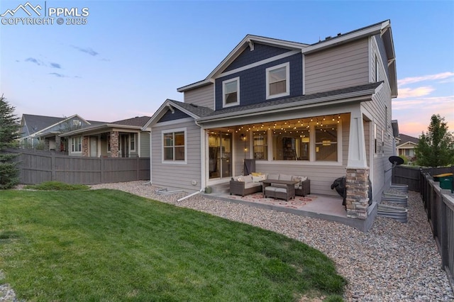 back of property at dusk featuring a yard, a patio, fence, and an outdoor living space