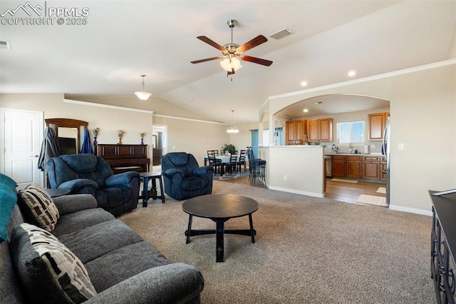 living area with light carpet, visible vents, vaulted ceiling, and arched walkways