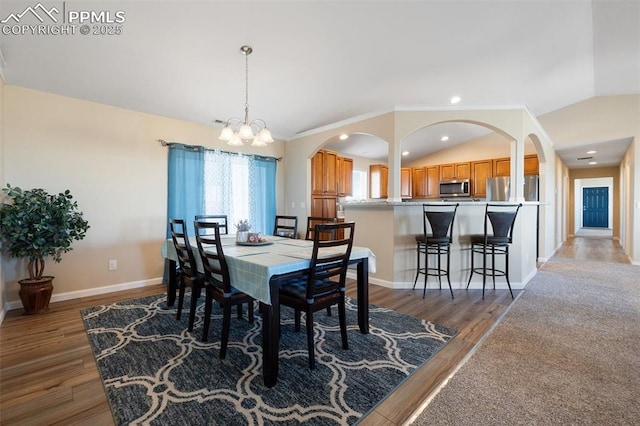 dining room with recessed lighting, wood finished floors, baseboards, vaulted ceiling, and an inviting chandelier