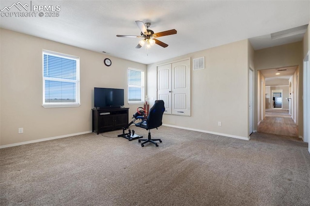 home office with a ceiling fan, light colored carpet, visible vents, and baseboards