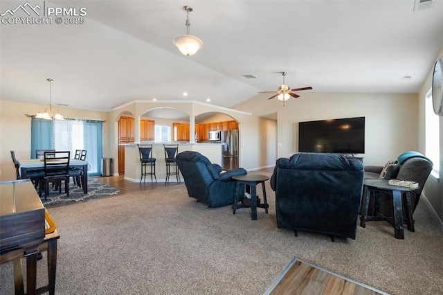 carpeted living room with arched walkways, visible vents, vaulted ceiling, baseboards, and ceiling fan with notable chandelier