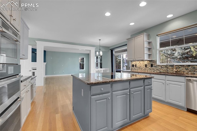 kitchen featuring hanging light fixtures, appliances with stainless steel finishes, gray cabinets, and a center island