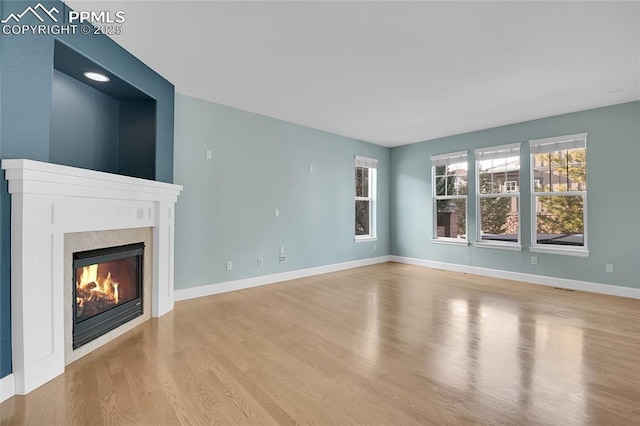 unfurnished living room featuring light wood-style floors, baseboards, and a premium fireplace