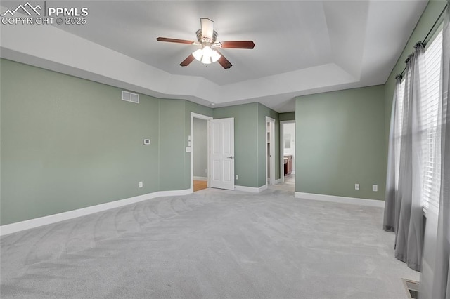 interior space featuring light carpet, a tray ceiling, visible vents, and baseboards