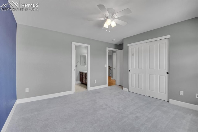 unfurnished bedroom with ceiling fan, light colored carpet, baseboards, a closet, and ensuite bath