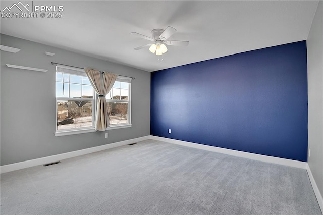 carpeted empty room with visible vents, ceiling fan, and baseboards