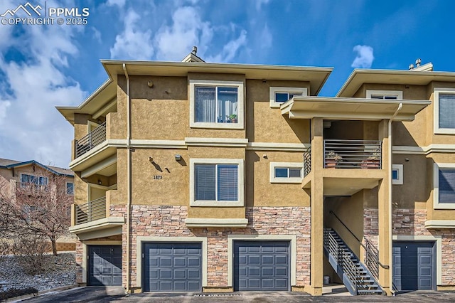 view of front of home with stone siding, stairway, an attached garage, and stucco siding