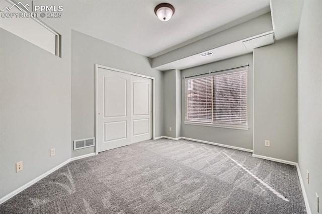 unfurnished bedroom featuring carpet floors, attic access, visible vents, and baseboards