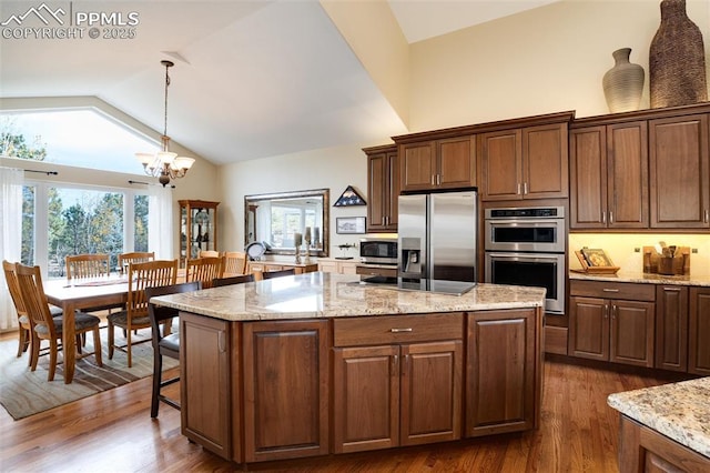 kitchen with hanging light fixtures, appliances with stainless steel finishes, dark wood-type flooring, and a center island