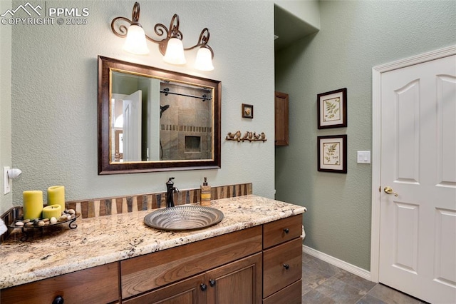 full bath featuring a shower, vanity, and baseboards