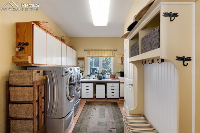 washroom featuring light wood-type flooring, washing machine and dryer, and cabinet space