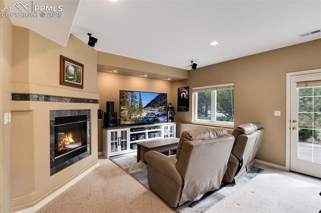 living area featuring carpet floors, a high end fireplace, a wealth of natural light, and visible vents