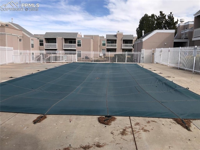 community pool with a patio area, a residential view, and fence