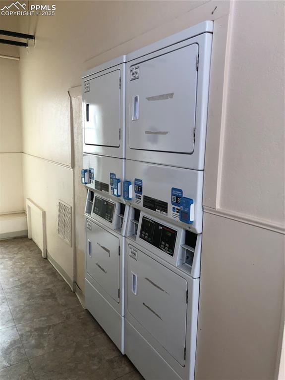 common laundry area featuring stacked washing maching and dryer and visible vents
