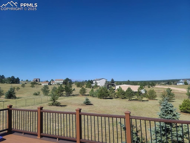 deck featuring a rural view, a lawn, and fence