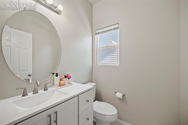 bathroom with baseboards, vanity, and toilet