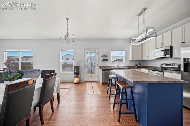 kitchen with dark countertops, a breakfast bar, a center island, stainless steel appliances, and light wood-type flooring