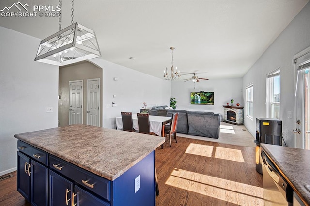 kitchen with blue cabinetry, a kitchen island, wood finished floors, dishwasher, and a lit fireplace