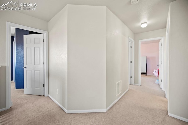 hall featuring carpet floors, baseboards, and visible vents