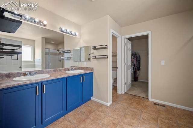 bathroom with double vanity, a shower stall, visible vents, and a sink