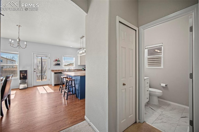 bathroom featuring baseboards, toilet, marble finish floor, an inviting chandelier, and a closet