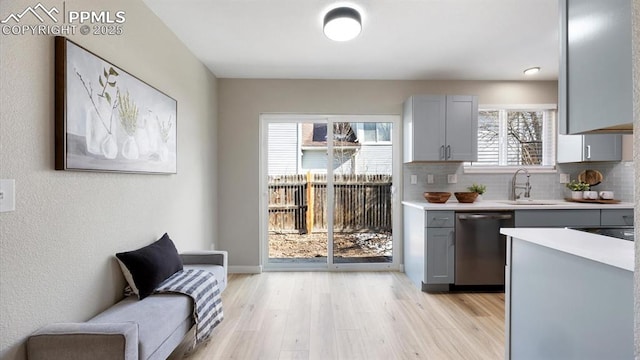 kitchen featuring gray cabinets, light countertops, dishwasher, and light wood finished floors