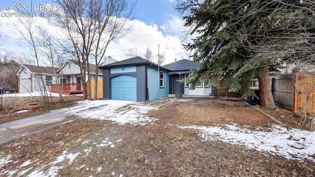 single story home with driveway, an attached garage, and fence