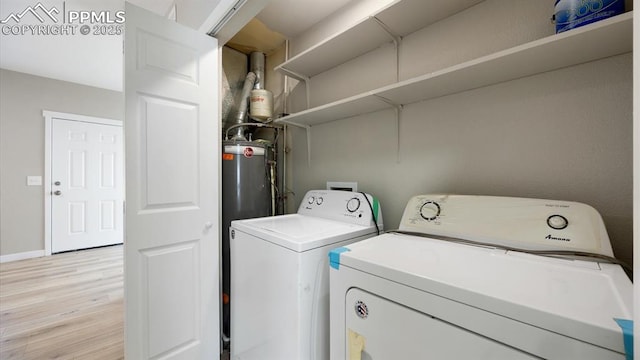 washroom featuring laundry area, baseboards, washer and clothes dryer, and light wood finished floors