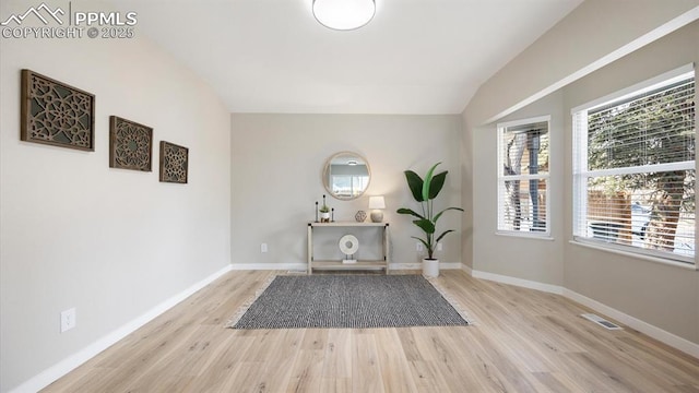 interior space with lofted ceiling, wood finished floors, visible vents, and baseboards