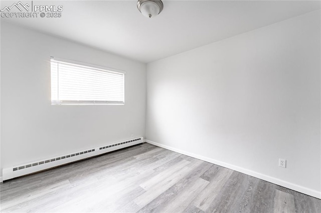 empty room featuring a baseboard heating unit and light wood-type flooring