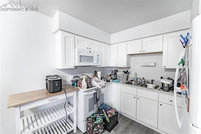 kitchen featuring sink, white appliances, white cabinets, and hardwood / wood-style floors