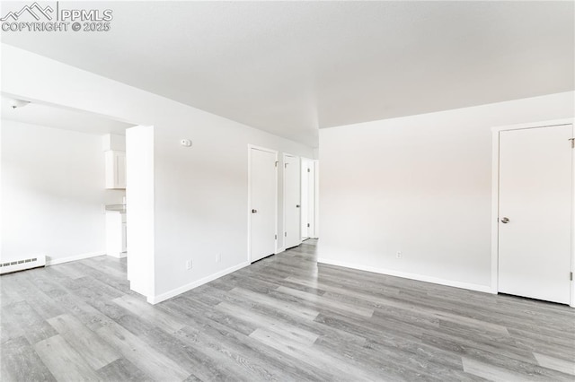 empty room with light wood-type flooring and a baseboard radiator