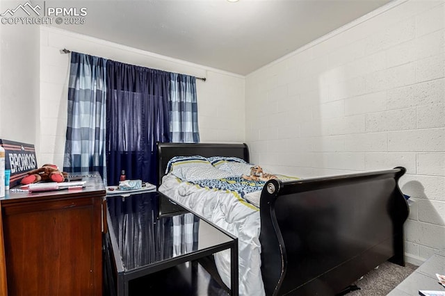 bedroom featuring concrete block wall