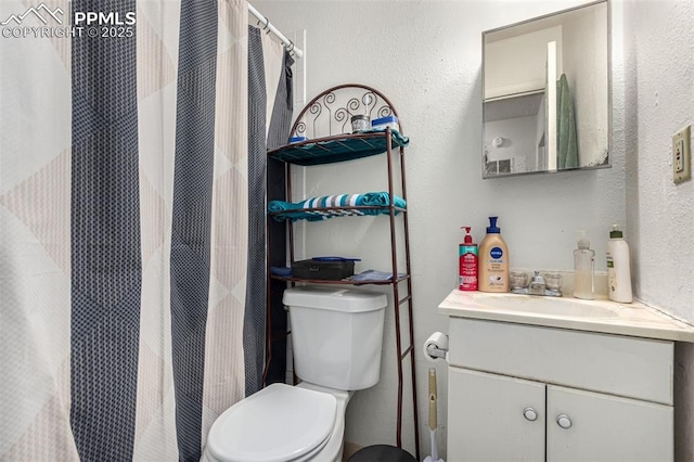 full bathroom featuring a textured wall, vanity, and toilet