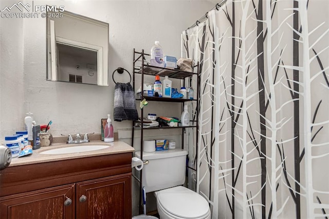 bathroom featuring toilet, a shower with shower curtain, and vanity