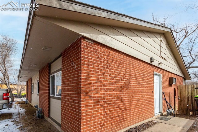 view of side of home featuring brick siding and fence