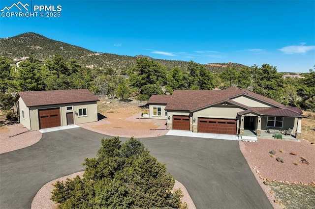 view of front of house featuring aphalt driveway, a garage, a view of trees, and a mountain view